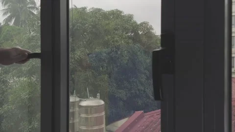 Hand Opening a Window with a Faint Reflection Overlooking a Tropical Yard Stock Footage 345145859