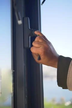 Hand opening a window handle in a bright coastal setting Photos
