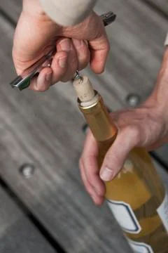 Hand opening a wine bottle with a corkscrew Stock Photos
