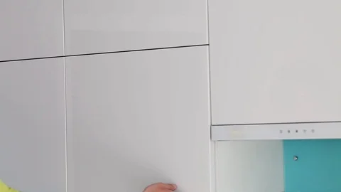 Hand opens and closes a cabinet in a modern white kitchen without handles. Stock Footage 127757716