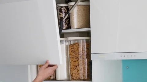 Hand opens and closes a cabinet in a modern white kitchen without handles. Stock Footage 127757757