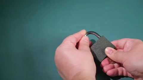 Hand opens and closes the padlock with a key on a turquoise background. Stock Footage 239851967