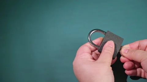Hand opens and closes the padlock with a key on a turquoise background. Stock Footage 239852053