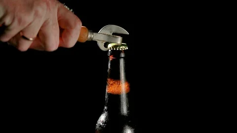 The hand opens a beer bottle opener on a black background Stock Footage 117726084