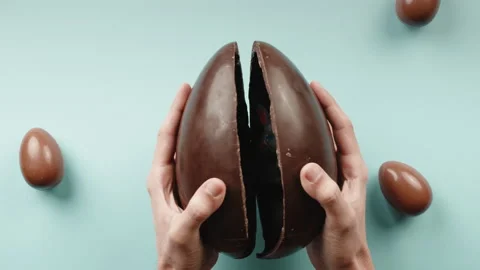 Hand opens a Chocolate Easter egg with a gift rabbit inside Stock Footage 175225758