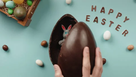 Hand opens a Chocolate Easter egg with a gift rabbit inside Stock Footage 175227899