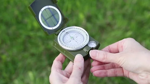 Hand opens a compass lid against a background of green grass Stock Footage 335327137