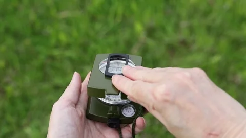 Hand opens a compass lid against a background of green grass Stock Footage 336632313