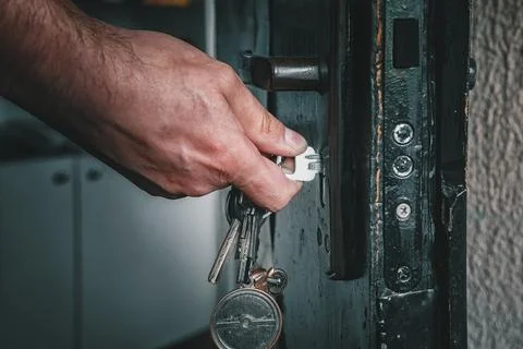 Hand opens the door with a key Stock Photos