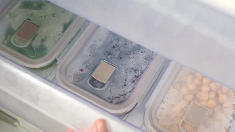 A hand opens a drawer in freezer with glass containers of frozen vegetables, top Stock Footage 318940732