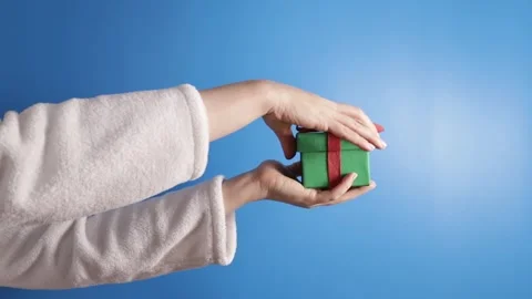 Hand opens a gift box on a blue background, Holiday present, merry wrapping.. Stock Footage 257331439