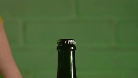 A hand opens a green beer bottle with a bottle opener Stock Footage 185028012