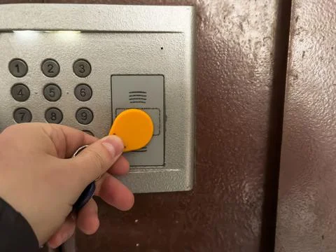 A hand opens the intercom with a yellow round magnetic key, the intercom in the 库存照片