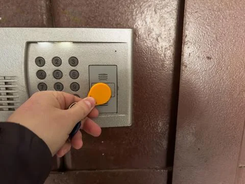 A hand opens the intercom with a yellow round magnetic key, the intercom in the 库存照片