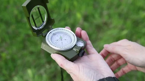 Hand opens the lid of an army compass against a background of green grass Stock Footage 335792842