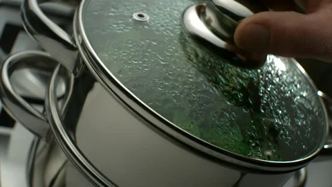 Hand opens the lid of a double boiler and shows how green broccoli is cooked Stock Footage 113604717