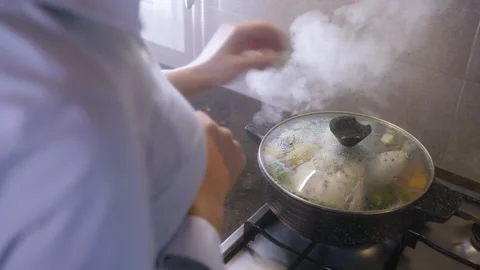 A hand opens the lid of a pot filled with boiled raw chicken and vegetables Stock Footage 132909755