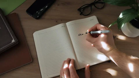 A hand opens a notebook and writes goals for the next year. Stock Footage 259822415