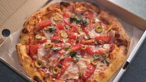A hand opens a pizza box to reveal a freshly made pizza topped with olives, Stock Footage 339004920