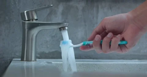 Hand opens tap brings toothbrush washes. Highlighting cleanliness video captures Stock Footage 270417165
