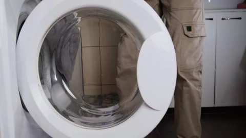 Hand opens washing machine and loads clothes, side view, laundry time, authentic 스톡 동영상 315112466