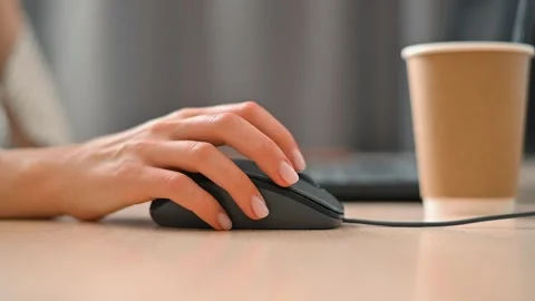 A hand operates a computer mouse on a desk while a coffee cup is positioned Stock Footage 339006031