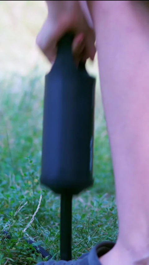 Hand operating air pump to inflate mattress on grass close up Stock Footage 340576917
