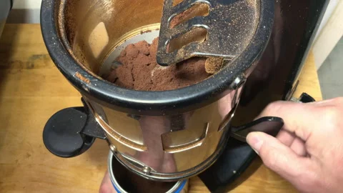 A hand operating the doser lever of a bean grinder, to release ground coffee. Video stock 281946608