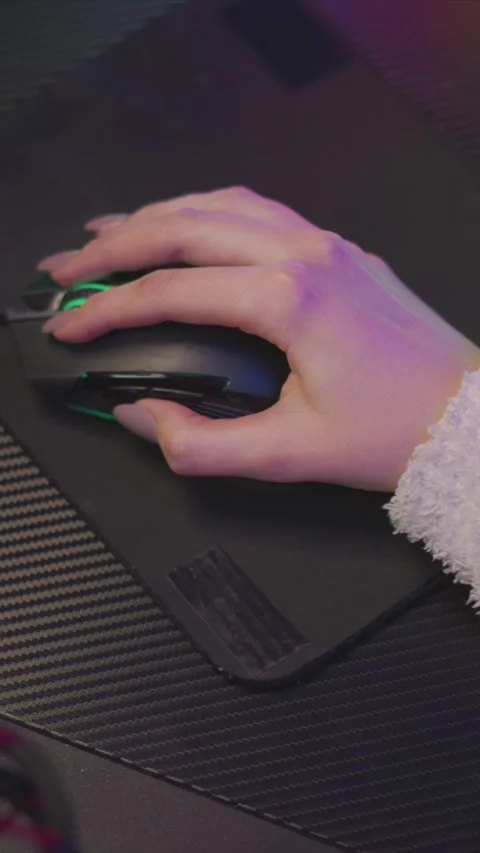 Hand operating gaming mouse on textured wrist rest under colorful ambient Stock Footage 348031924