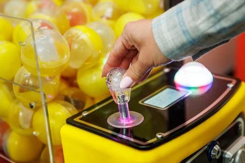 Hand operating joystick on yellow capsule toy machine Stock Photos