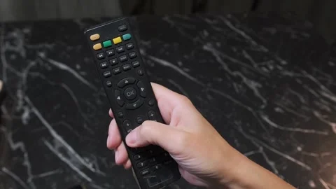 Hand operating TV remote close-up, clicking navigation button to control Stock Footage 333650044