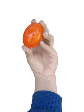Hand with an orange egg. Easter painted egg. Isolated object. Stock Photos