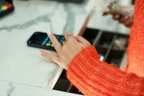 Hand in orange sleeve entering code on phone at register 스톡 사진