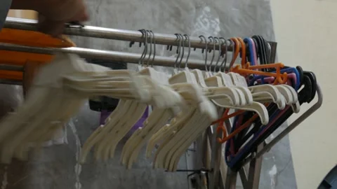 Hand Organizing Plastic Clothes Hangers on a Laundry Rack Close Up Stock Footage 341869152