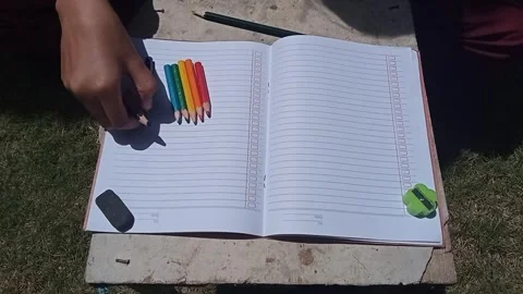 Hand organizing scattered colored pencils into a row next to a book. Stock Footage 313728592