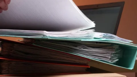 Hand organizing a tall stack of messy folders and numerous documents on a desk Stock Footage 347239177