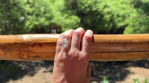 Hand with oval diamond engagement ring on wooden railing Mediterranean setting Stock Footage 319406909