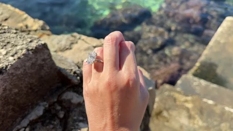 Hand with oval diamond ring resting on rocky coast Croatia Stock Footage 319693966