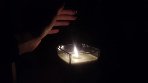Hand over a burning candle in the dark Stock Footage 294716775