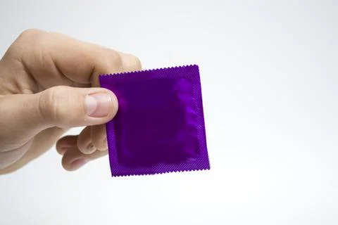Hand pack blue condom on a white background, concept protection against AIDS. Stock Photos