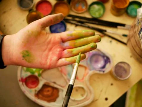 Hand in the paint of an art school student on the background of a palette Stock Photos