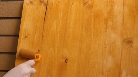 Hand with paint roller applying acrylic lacquer on wooden board Stock Footage 64417881