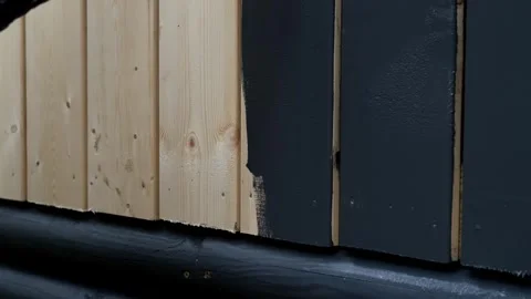 Hand with paint roller applying dark paint on wooden wall Stock Footage 322121189