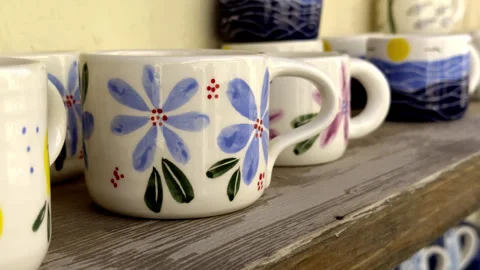 Hand-Painted Ceramic Coffee Mugs on a Wooden Shelf Stock Footage 347909503