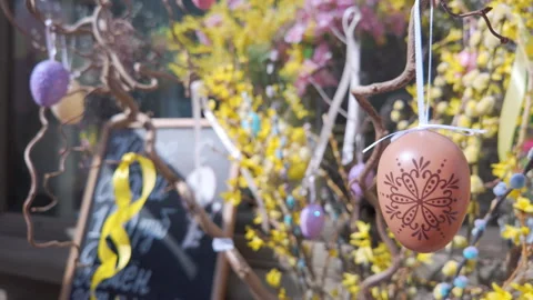 Hand painted Easter egg hangs on a branch among yellow spring flowers. Stock Footage 332129039