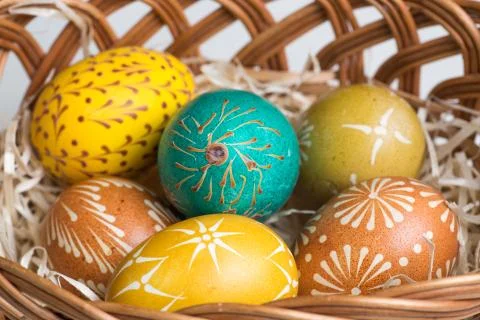 Hand-painted easter eggs in brown basket Stock Photos
