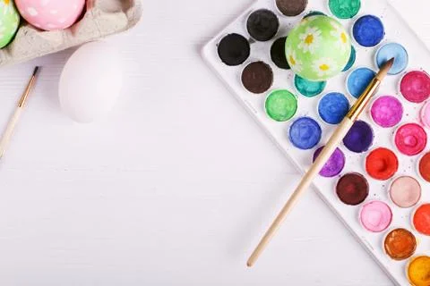 Hand painted Easter eggs, paints and brushes on a white table. Preparation fo Stock Photos