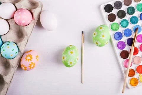 Hand painted Easter eggs, paints and brushes on a white table. Preparation fo Stock Photos