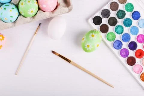 Hand painted Easter eggs, paints and brushes on a white table. Preparation fo Stock Photos