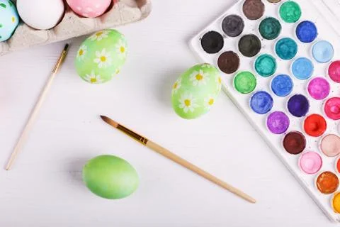 Hand painted Easter eggs, paints and brushes on a white table. Preparation fo Stock Photos
